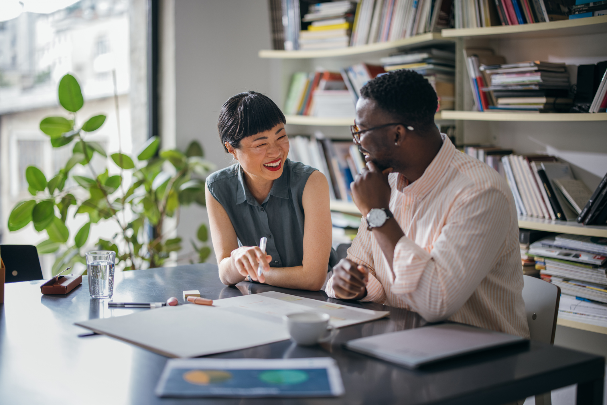 Two Happy Colleagues Talking While Working Together In The Office